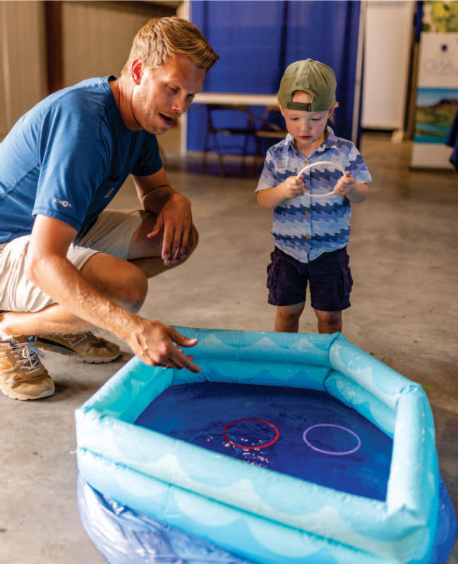 A man and a boy holding a ring; inflatable pool with a purple and red ring